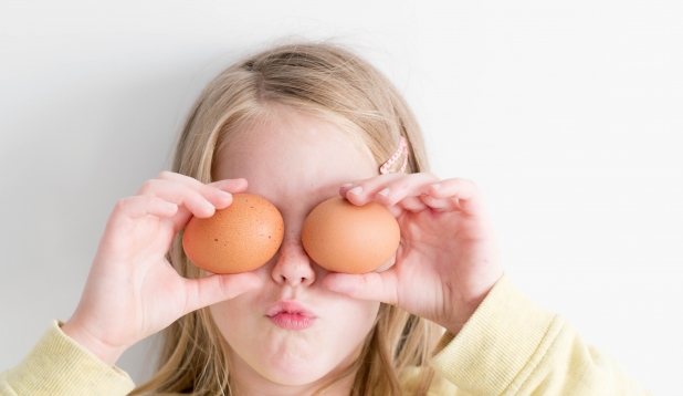 ein Kind haelt sich Eier vor die Augen