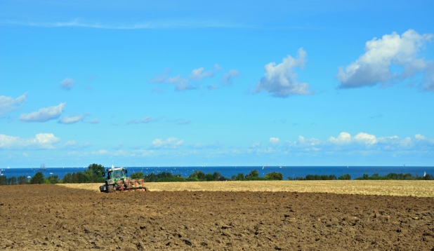 ein Landwirt pfluegt ein Feld an der Ostsee
